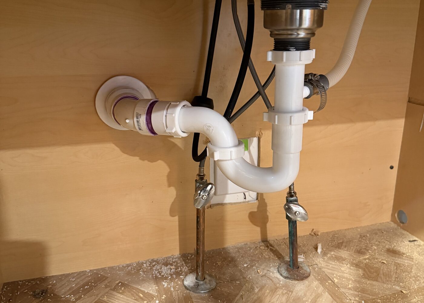 New sink drain trap and supply shutoffs installed under a vanity