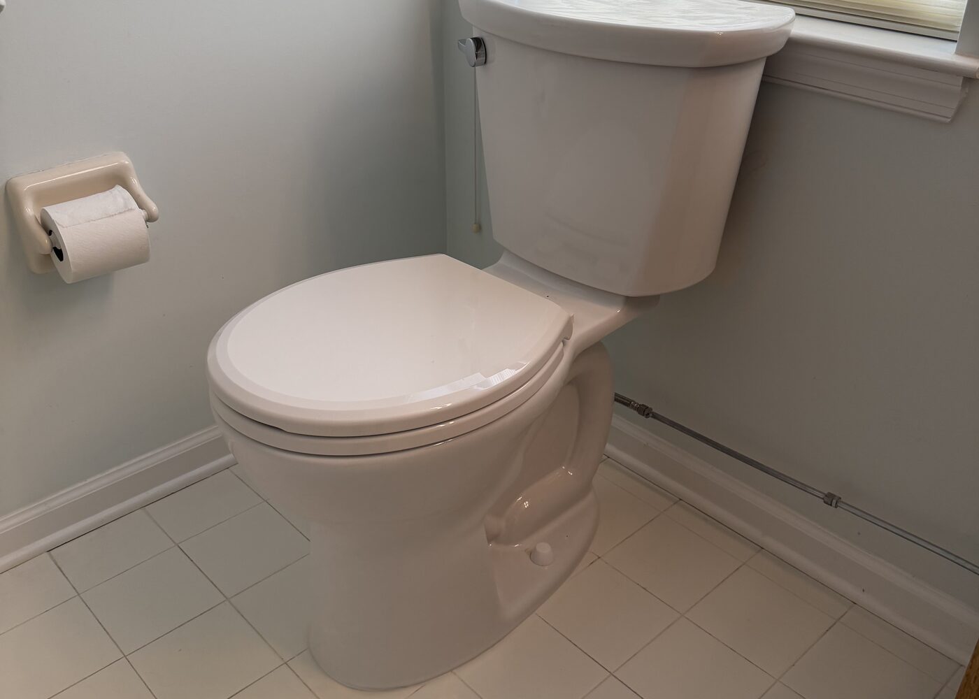 Clean white toilet installation beside a bathroom window